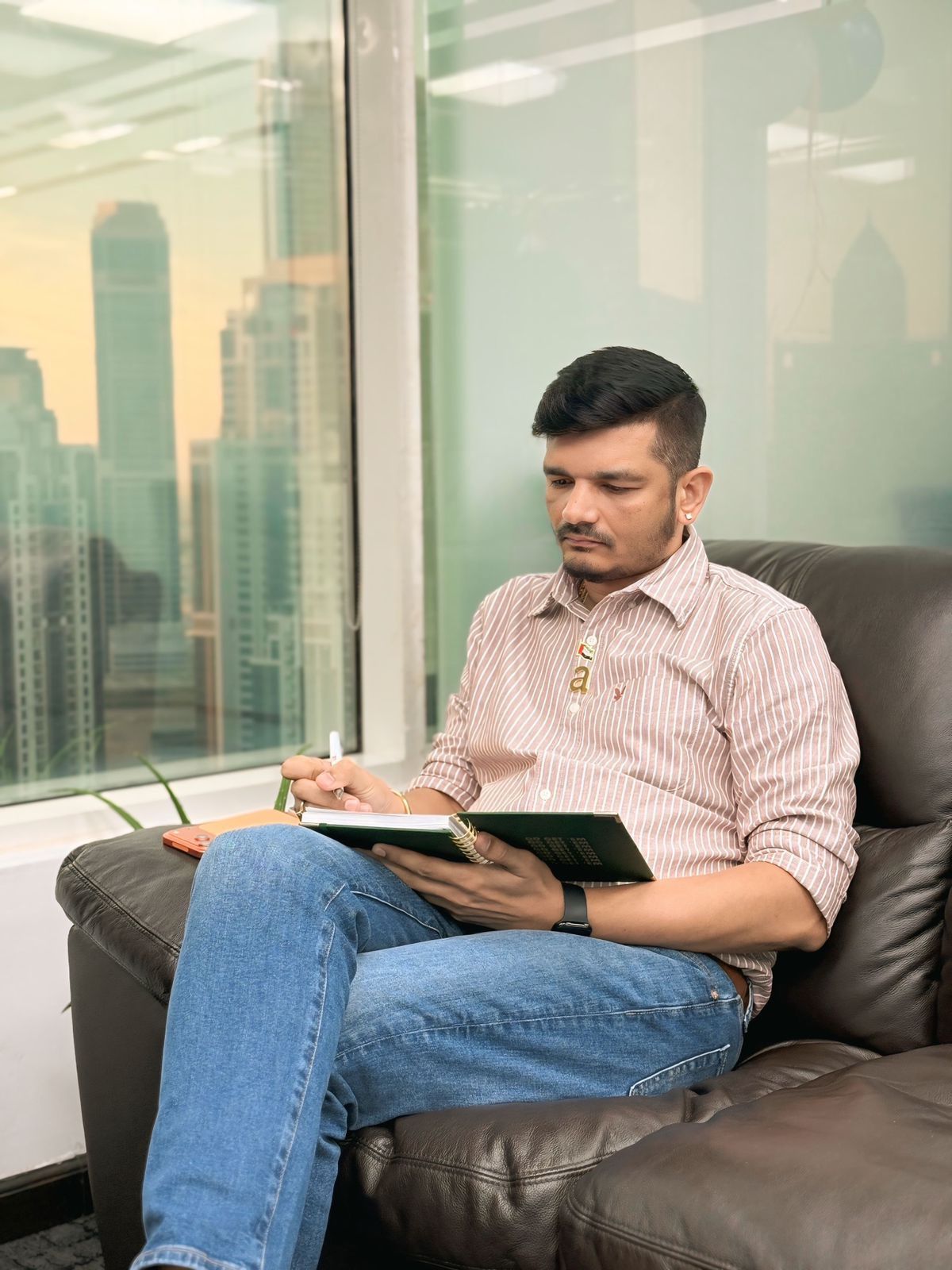 Priteesh Patel writing beside a city-view window